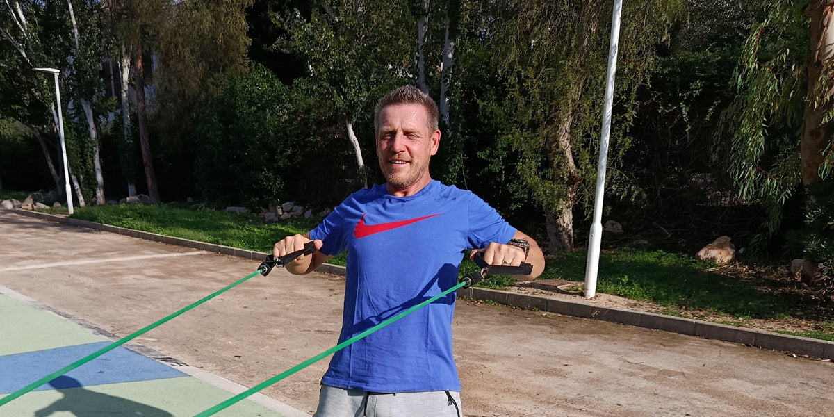 Fysiotherapeut Jos traint buiten met een groen sportelastiek