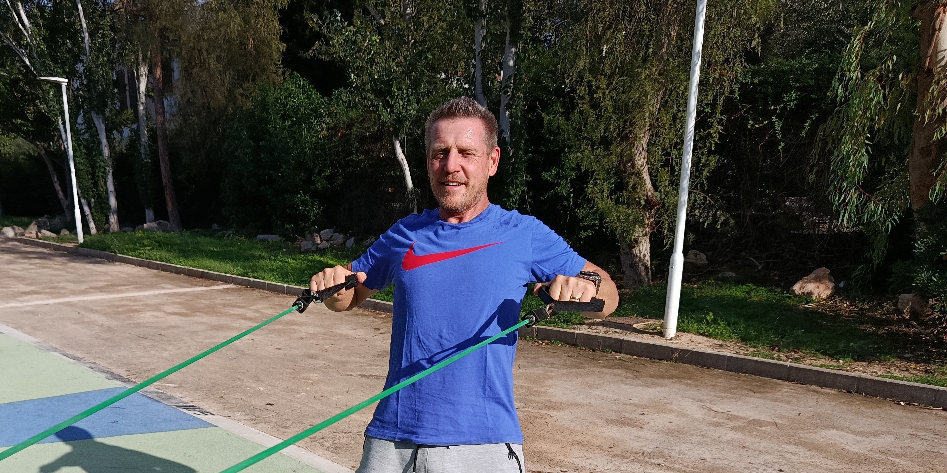 Fysiotherapeut Jos traint buiten met een groen sportelastiek